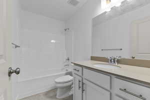 Bathroom featuring tub / shower combination, vanity, toilet, and visible vents