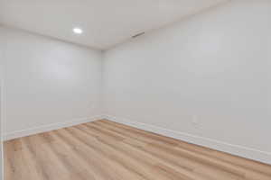 Spare room with recessed lighting, baseboards, light wood-type flooring, and visible vents