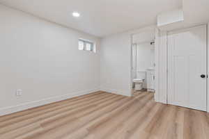 Unfurnished bedroom with light wood-type flooring, recessed lighting, baseboards, and ensuite bathroom
