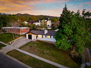 View of front facade with driveway, a chimney, a mountain view, a front lawn, and an attached garage