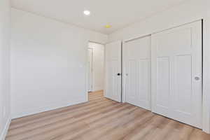 Unfurnished bedroom with light wood-type flooring, recessed lighting, baseboards, and a closet