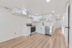 Kitchen with stainless steel appliances, baseboards, a sink, and light wood-style floors