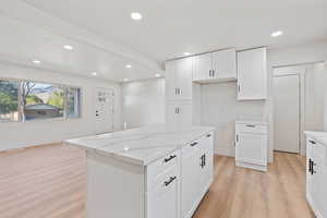 Kitchen with light wood-style floors, light stone countertops, recessed lighting, and white cabinetry