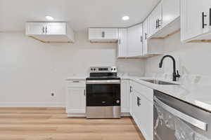 Kitchen featuring a sink, appliances with stainless steel finishes, and white cabinets