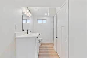 Bathroom featuring visible vents, wood finished floors, vanity, baseboards, and toilet