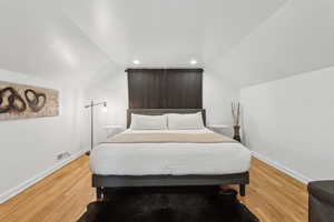 Large Top floor primary bedroom with recessed lighting, king bed, and hardwood floors.