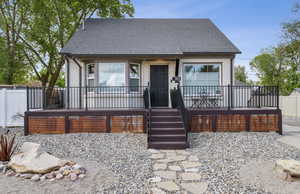 View of front of house featuring a wrap around deck, fence, and roof with shingles