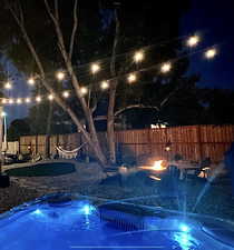 View at night with a hot tub, a fire pit, and a fenced private backyard.