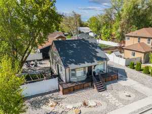 View of front of home with deck, a shingled roof, and a fenced backyard
