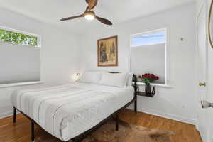 Bedroom featuring King bed,  a ceiling fan, baseboards, and hardwood / wood-style floors