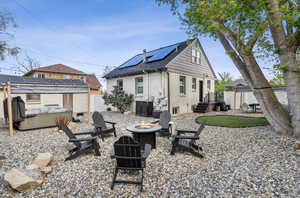Back of property with a fire pit, a patio, a fenced backyard, brick siding, and solar panels