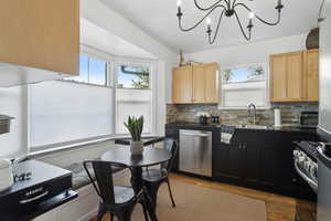 Kitchen featuring light newer cabinetry, concrete countertops, stainless steel appliances, a healthy amount of sunlight, and hardwood flooring
