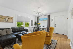 Living area featuring an inviting chandelier, baseboards, and hardwood floors