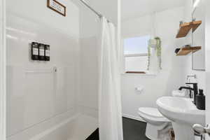 Full bathroom featuring tile patterned floors, a wainscoted wall, a shower/bath, updated fixtures and shelving.
