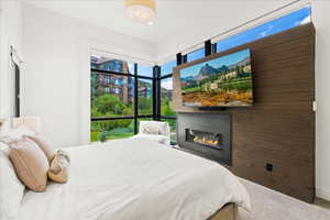 Bedroom featuring carpet and a glass covered fireplace