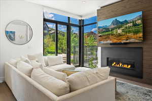 Living area featuring a healthy amount of sunlight, a glass covered fireplace, recessed lighting, and wood finished floors