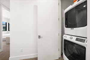 Clothes washing area featuring stacked washing maching and dryer, carpet floors, and laundry area