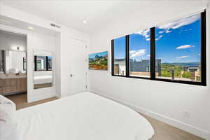 Carpeted bedroom with recessed lighting, baseboards, visible vents, and ensuite bathroom