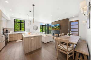 Kitchen with light brown cabinetry, high end stainless steel range, light wood-style floors, modern cabinets, and a center island