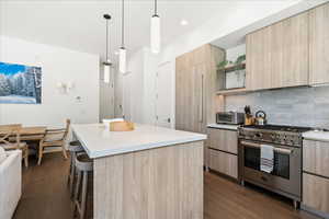 Kitchen featuring light brown cabinetry, modern cabinets, and high end range