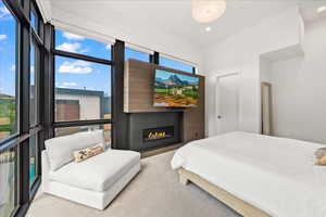 Carpeted bedroom with recessed lighting and a glass covered fireplace