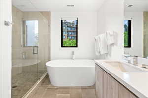 Bathroom featuring vanity, visible vents, a soaking tub, and a stall shower