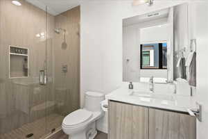 Bathroom with vanity, a stall shower, toilet, and visible vents