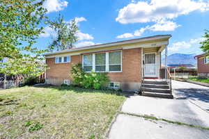 View of front of house with brick siding, fence, and a front yard