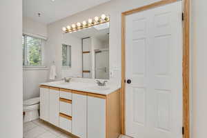 Full bath featuring double vanity, a sink, tile patterned floors, and toilet