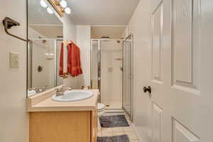 Full bathroom featuring vanity, a stall shower, tile patterned floors, and toilet