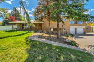 View of front of property with fence, an attached garage, a front lawn, brick siding, and decorative driveway