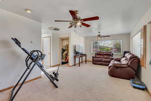 Workout room with light colored carpet, a ceiling fan, and baseboards