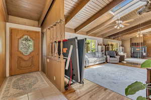 Foyer entrance featuring ceiling fan, wooden ceiling, and vaulted ceiling with skylight