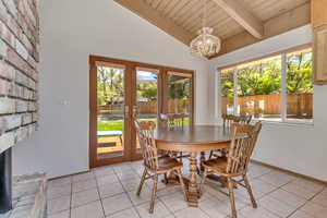Dining space with baseboards, vaulted ceiling with beams, wooden ceiling, french doors, and a notable chandelier