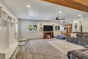 Living area with wood finished floors, baseboards, recessed lighting, a baseboard heating unit, and a ceiling fan