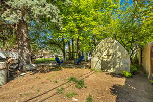 View of yard featuring a storage shed, an outbuilding, a fenced backyard, and a fire pit