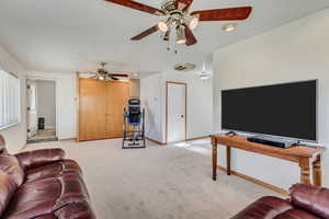 Living room featuring a ceiling fan, baseboards, and light carpet