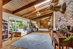 Living area featuring wood ceiling, ceiling fan, brick wall, and wood finished floors