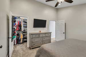 Bedroom featuring a closet, a towering ceiling, light carpet, a spacious closet, and a ceiling fan