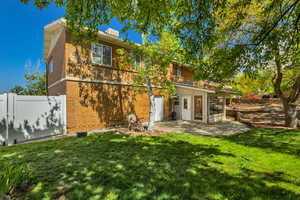 Rear view of property with fence, a yard, a patio area, and brick siding