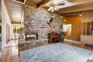 Living room featuring ceiling fan, wood finished floors, stairway, wooden ceiling, and beamed ceiling