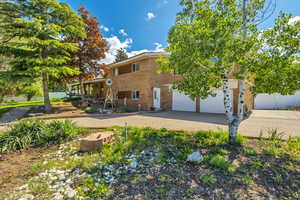 View of front of home featuring brick siding, decorative driveway, and fence
