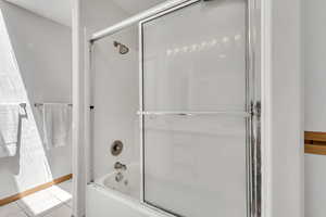 Full bath featuring enclosed tub / shower combo and tile patterned floors
