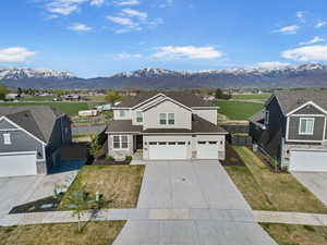 Traditional home with a garage, fence, stone siding, and concrete driveway