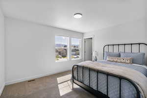 Carpeted bedroom featuring baseboards and visible vents