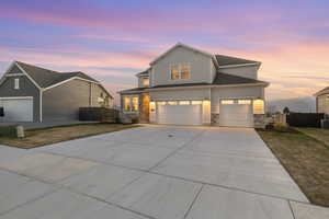 Traditional-style home with a yard, fence, driveway, and stone siding