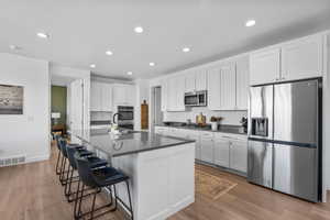 Kitchen featuring dark countertops, stainless steel appliances, white cabinetry, and visible vents