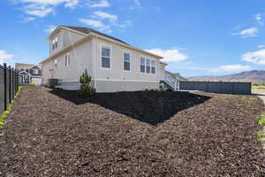 View of property exterior with fence, a mountain view, and central AC