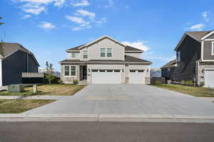 View of front of house featuring concrete driveway, an attached garage, stone siding, and a front lawn