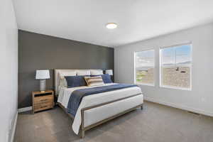 Carpeted bedroom featuring baseboards and visible vents